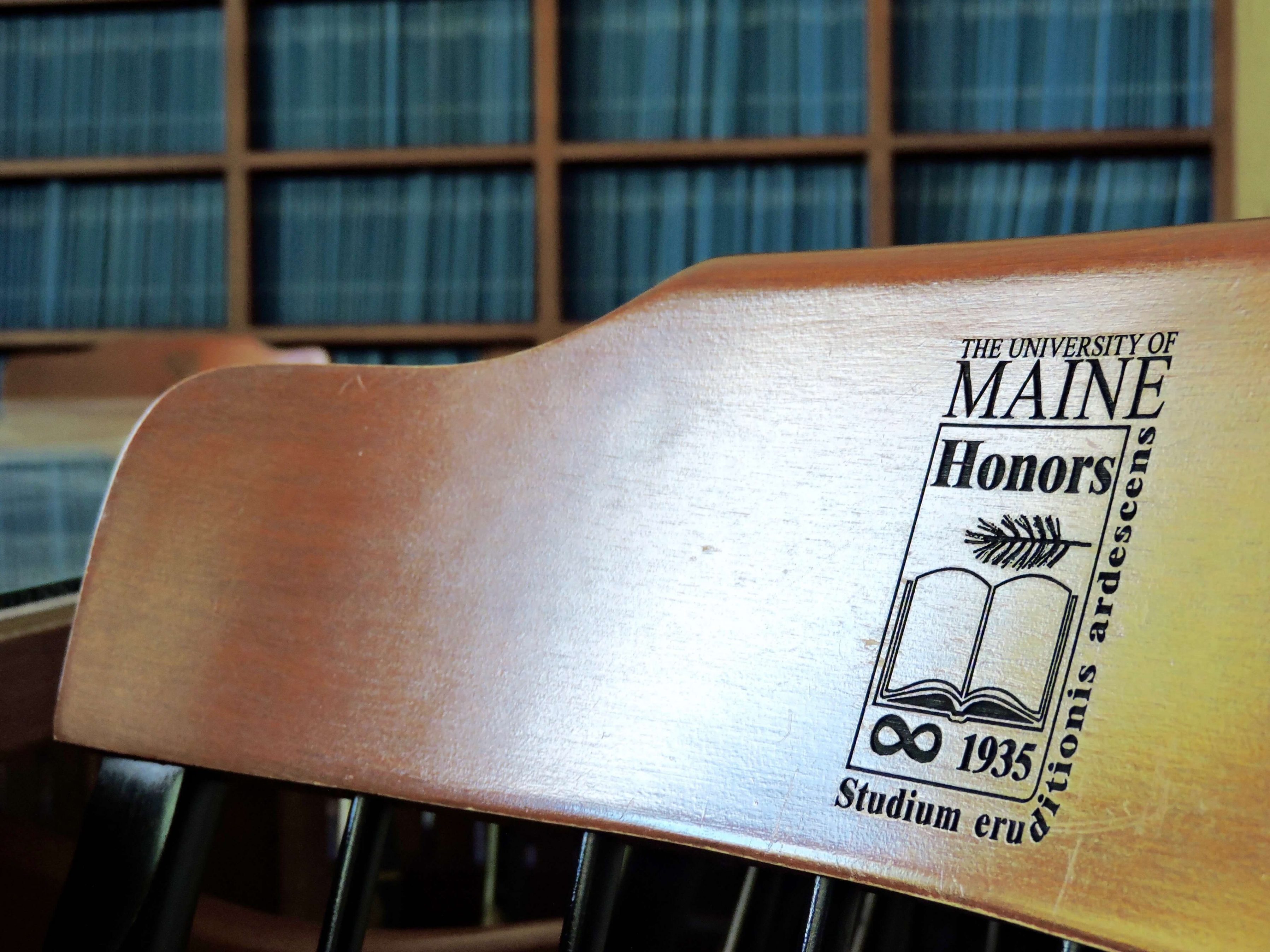 Honors chair in the thesis reading room, with bookshelves of theses shown behind it.