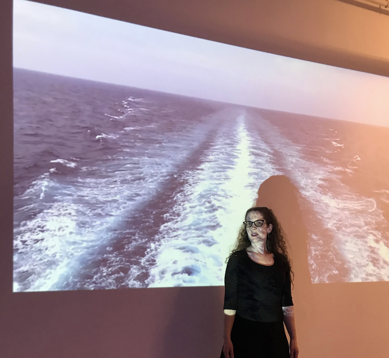 Samantha Jones is shown with a projection of the ocean