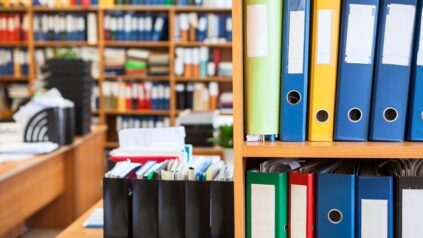 Stock image of binders and forms on a bookshelf