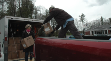 Community members load boxes of food for donation into a truck.