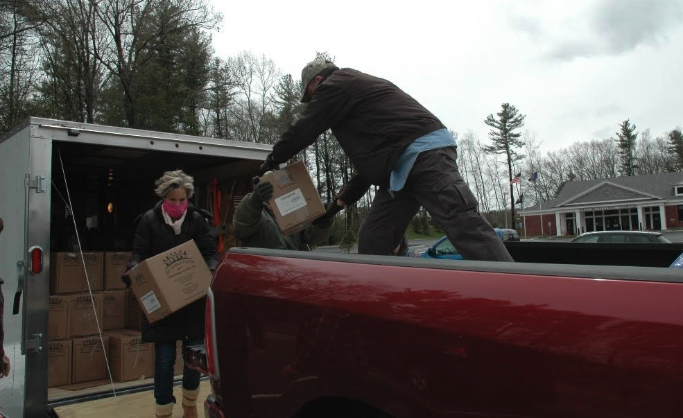 Community members load boxes of food for donation into a truck.