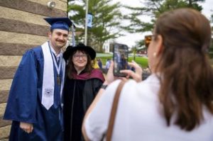 Dr. Ladenheim and a student posing for a picture together in graduation regalia